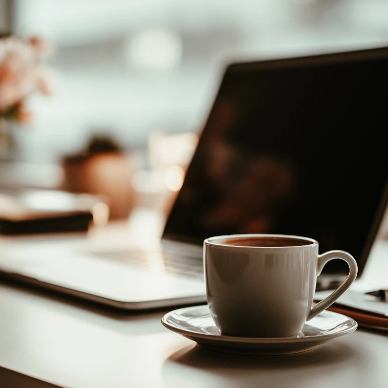 kaffekopp, laptop och blomkruka i stämningsfull bild